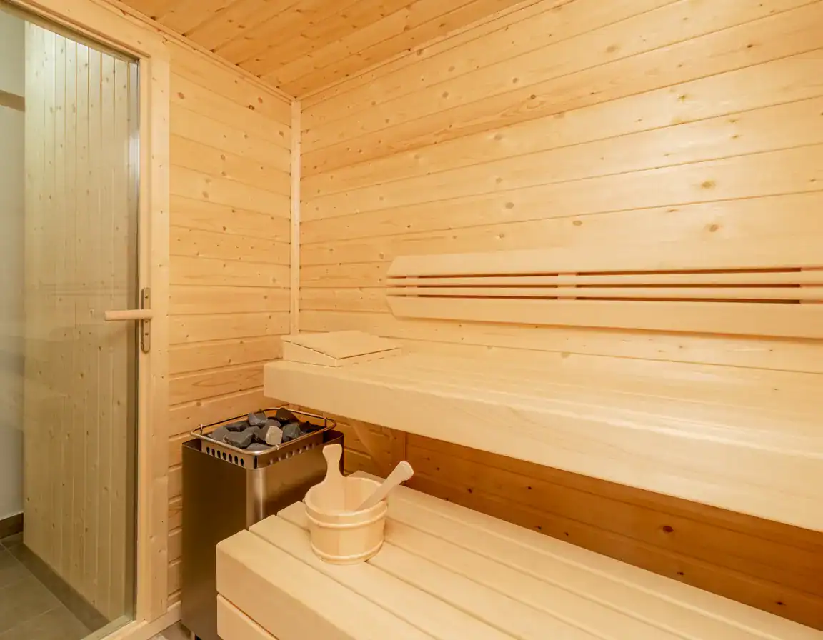 Intérieur d'un sauna en bois clair avec bancs et sauna à infrarouge.